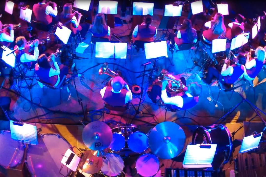 Foto von oben auf die Blaskapelle auf der Bühne, die blau beleuchtet ist.