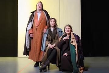 Drei Personen, der Größe nach aufgereiht, in 1920er Kleidung auf der Bühne.